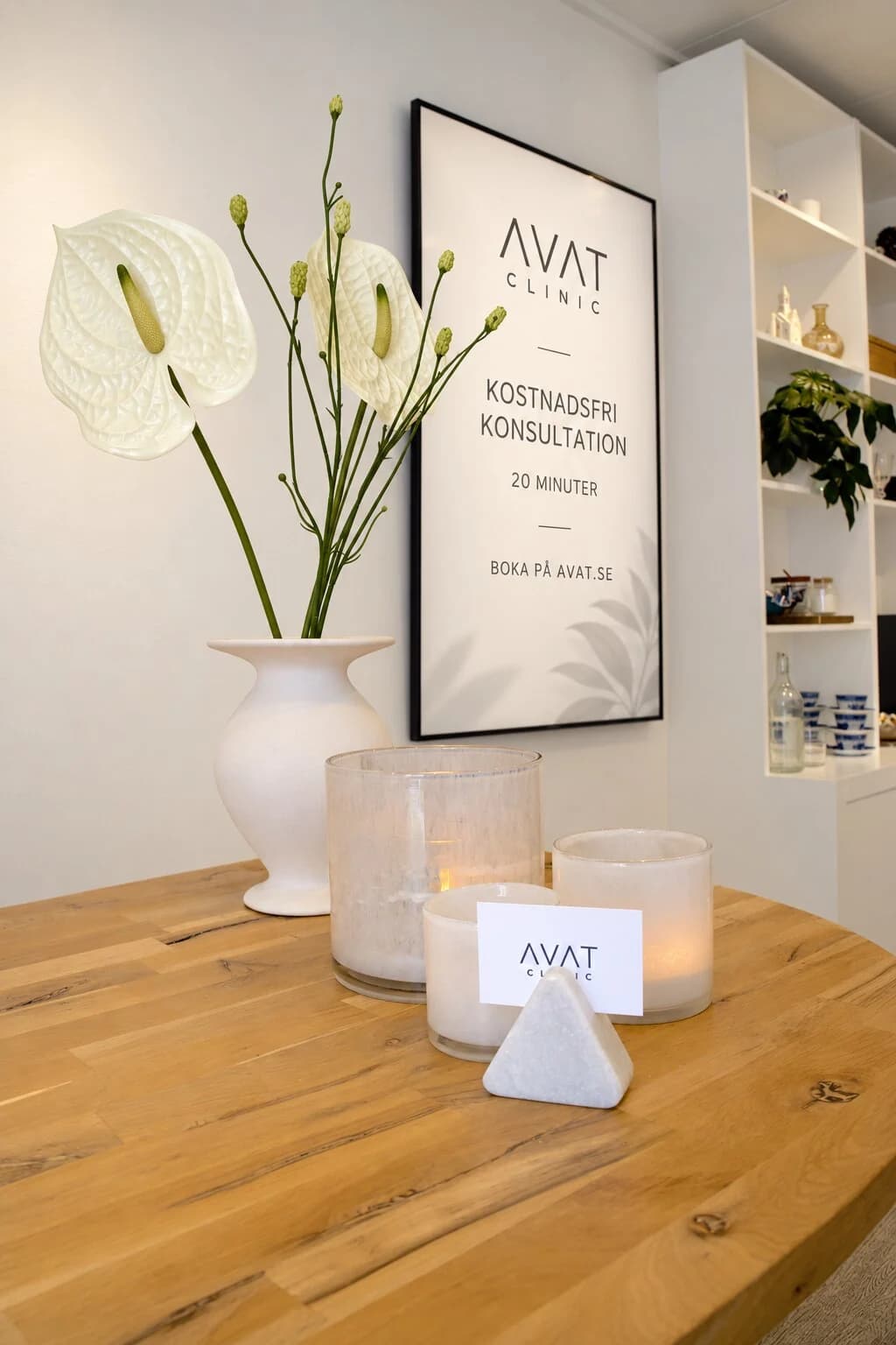 Inramad affisch om kostnadsfri konsultation hos Avat Clinic, med blommor och ljus